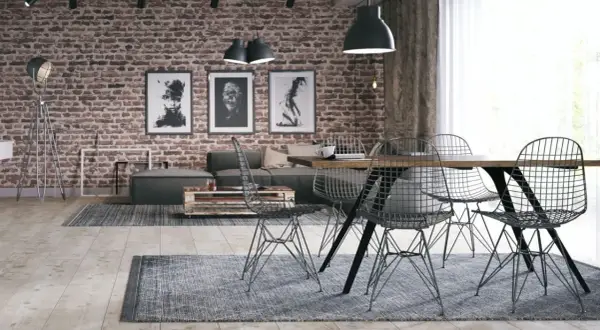 Surowy, betonowy sufit w stylu loft nadaje wnętrzu industrialnego charakteru. Ceglana ściana, grafiki i metalowe meble dopełniają ten surowy klimat.