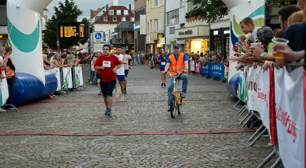 Läufer und Radfahrer beim Stadtlauf Bergisch Gladbach. Zuschauer jubeln am Streckenrand.