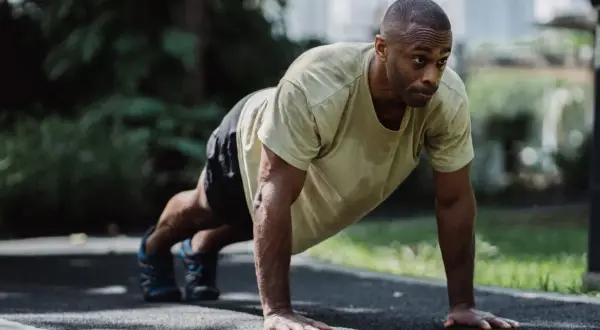 A determined boxer performs push-ups outdoors. This exercise builds the upper body strength crucial for delivering powerful punches and absorbing blows.
