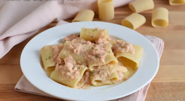 Piatto di paccheri conditi con un cremoso sugo di pasta al salmone fresco, guarnito con erba cipollina.