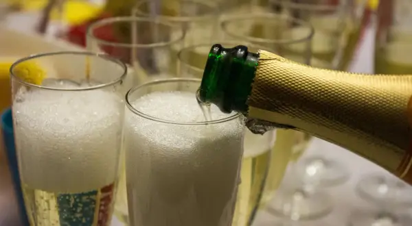 Schaumiger Prosecco wird in Gläser gegossen. Aber kann Prosecco schlecht werden? Ja, wenn er falsch gelagert wird.