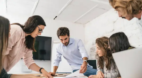 Equipo colaborando en un proyecto, demostrando un alto coeficiente emocional al comunicarse y resolver problemas juntos.