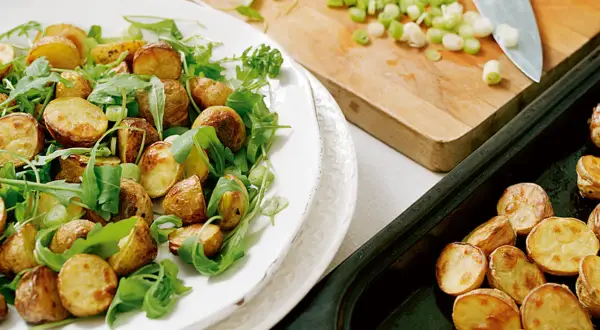 En härlig rostad potatissallad med ruccola och salladslök, redo att serveras.