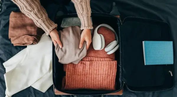 Packa smart! Här ser du vad som kan vara bra att ha i handbagaget på flyget: kläder, hörlurar och en anteckningsbok.