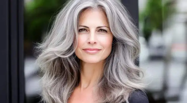Donna con splendidi tagli capelli grigi, lunghi e ondulati, che incorniciano un viso sorridente.