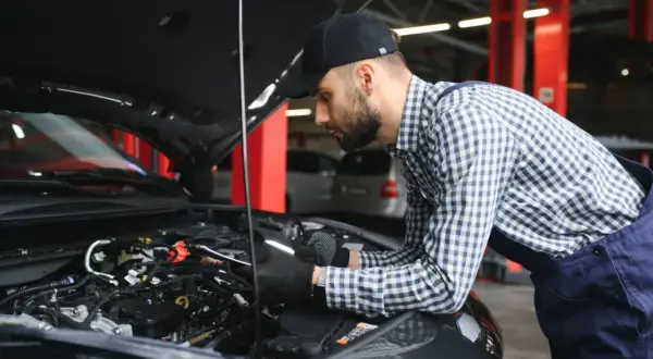 Mechanik w warsztacie sprawdza stan cewek zapłonowych w silniku samochodu.
