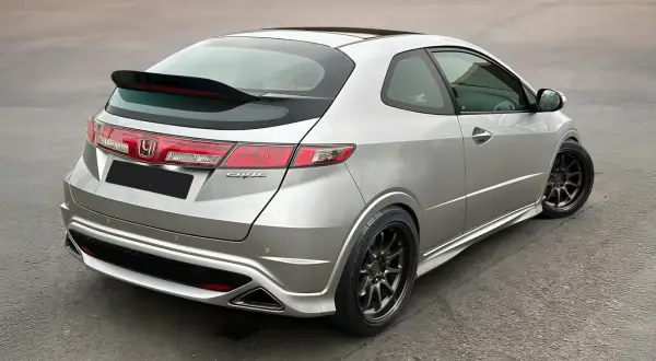 Srebrny Honda Civic VIII z czarnym spoilerem na klapie bagażnika i przyciemnianymi felgami.
