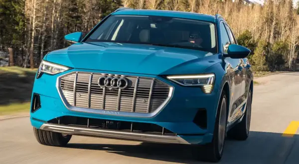 Blå Audi e-tron kör på en väg i skogen. En begagnad Audi e-tron som är perfekt för äventyr.