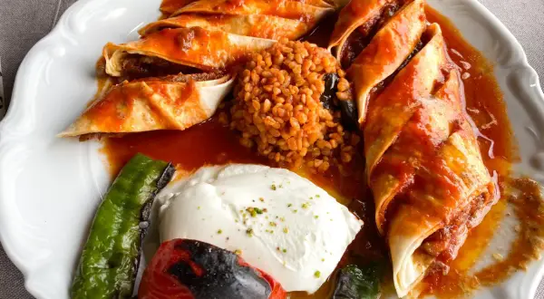 Pyszne jedzenie w Turcji: roladki z mięsem w sosie pomidorowym, bulgur i grillowane warzywa z jogurtem.