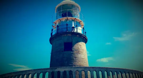 El faro de Corrubedo se alza imponente bajo un cielo azul intenso.