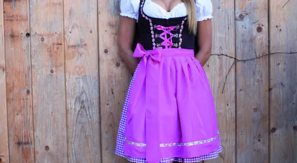 Dirndl mit pinkem Satinband-Schnürung und passender Schleife. Darunter ein karierter Unterrock.