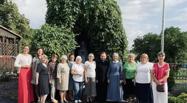Grupa osób z księdzem i siostrą zakonną przy kapliczce Matki Bożej. Odnowa w duchu świętym zagrożenia, nadzieja w wierze.