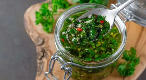 Sos chimichurri do mięsa z grilla przepis: świeża pietruszka, czosnek, chili i oliwa w słoiku. Idealny dodatek do grillowanych przysmaków.