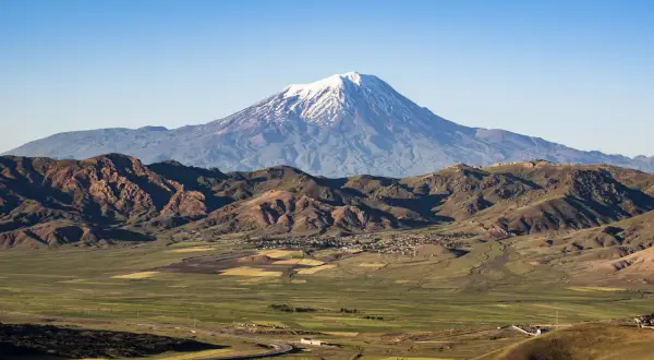 Majestatyczny masyw wulkaniczny w Turcji, Ararat, góruje nad zieloną doliną z polami uprawnymi i krętą drogą.