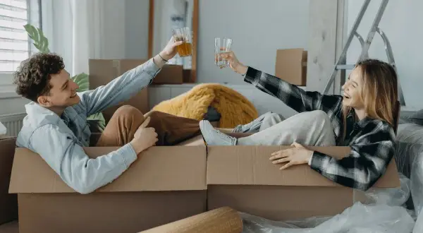 Pareja brindando dentro de cajas, listos para mudarse. ¡Qué alivio que mi casero quiere hacer obras y nos da esta oportunidad!