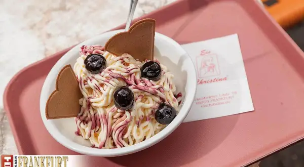 Ein süßes Delfino Eis mit Kirschen und Waffelherzen, serviert auf einer rosa Schale.