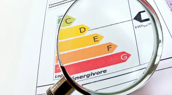Loupe sur un diagnostic de performance énergétique (DPE). La classification de A à G, indiquant une interdiction location, est examinée.