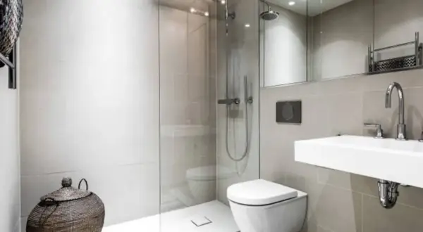 Moderno bagno senza finestra con doccia a filo pavimento, WC sospeso, lavabo minimalista e cesto in vimini.