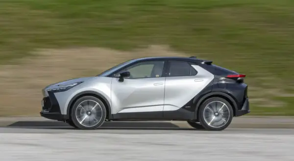 Srebrno-czarny Toyota C-HR 2019 w ruchu, z rozmytym tłem zieleni i drogi.