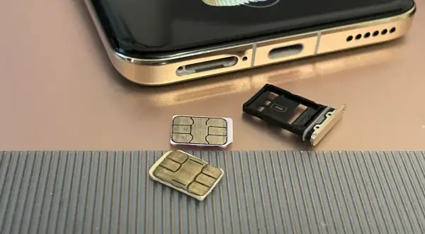 Dwie karty SIM i tacka na karty obok telefonu. Czy można mieć dwie karty SIM z tym samym numerem? To pytanie nurtuje wielu użytkowników.