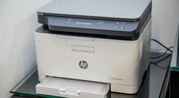 Biała drukarka HP z panelem sterowania i wysuniętą szufladą na papier. Idealna do domu, bo to drukarka tania w eksploatacji.