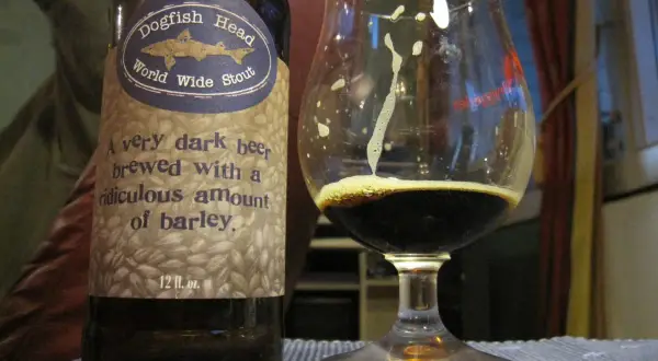 Una bottiglia e un bicchiere di Dogfish Head World Wide Stout, una birra scura con un significato di abbondante orzo.