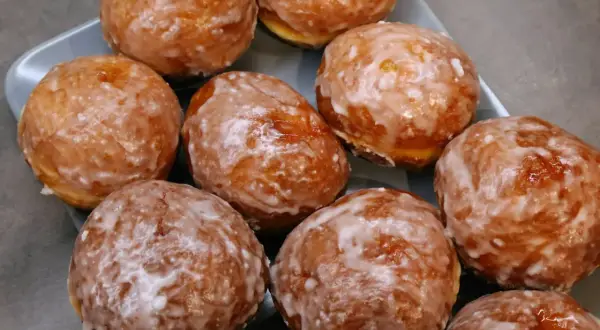 Pyszne, rumiane pączki z piekarnika, oblane lukrem, kuszą swoim wyglądem. Idealne na tłusty czwartek!