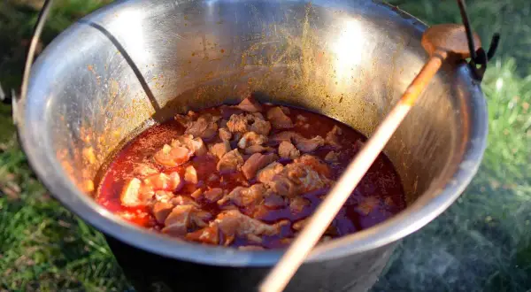 Pyszne dania z kociołka żeliwnego przepisy w akcji! Mięso dusi się w aromatycznym sosie, gotowe do podania.