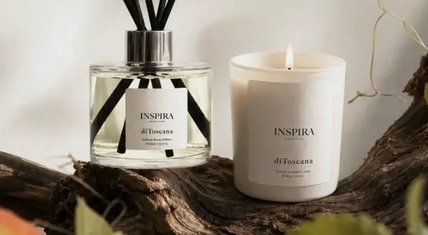 Dyfuzor i świeca Inspira "di Toscana" na tle drewna. Te zapachy tworzą własne, piękne histoires de parfums.
