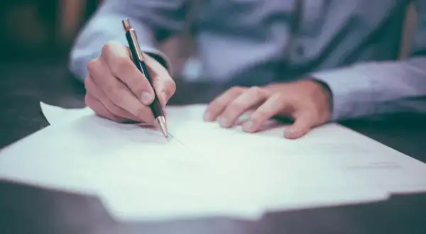 Dłoń pisze na papierze, zastanawiając się, ile czasu ma sąd na odpowiedź z sądu.
