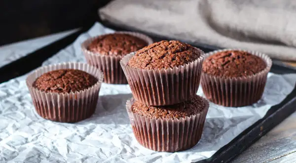 Fem chokladmuffins på ett bakplåtspapper. Perfekt för ett enkelt cupcakes recept.