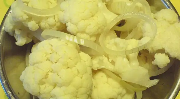 Blumenkohl und Zwiebelringe für blumenkohl sauer einlegen in einer Schüssel.