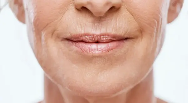 Primo piano del volto di una donna anziana, con particolare attenzione alle labbra e alle rughe labiali che raccontano storie di vita.