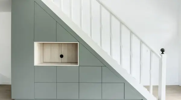 Aménagement sur mesure : un rangement sous escalier gris pâle avec des portes et une niche en bois clair.