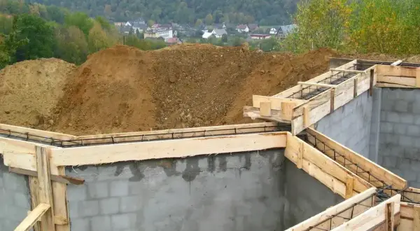 Fundamenty domu w budowie, zbrojenie i szalunki czekają na beton. Ważne pozwolenie na budowę to klucz do legalnego stawiania wymarzonego domu.