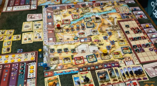 Plansza do gry "Great Western Trail Argentyna" z kartami bydła i pionkami. Gracze prowadzą swoje stada przez rozległe tereny.