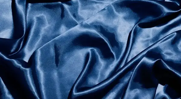 Gładkie, granatowe tkaniny satynowe układają się w eleganckie fałdy, odbijając światło.