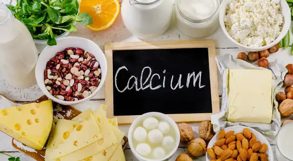 Talerzyk z serem, fasolą, orzechami i mlekiem. Tabliczka z napisem "Calcium" przypomina o ważnym składniku odżywczym.