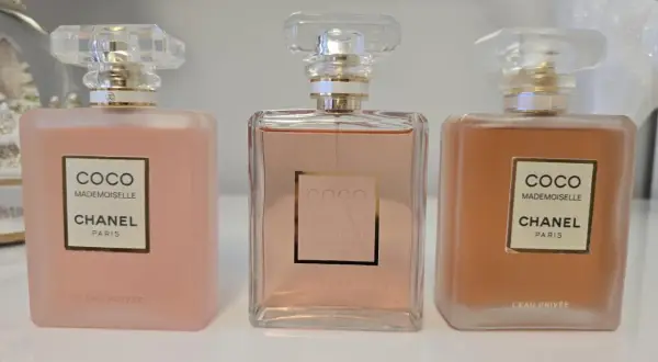 Trzy flakony Chanel Coco Mademoiselle L'Eau Privée w odcieniach różu i brzoskwini.