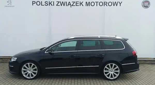 Czarny Volkswagen Passat kombi, model r36, zaparkowany przed budynkiem z logo Polskiego Związku Motorowego.