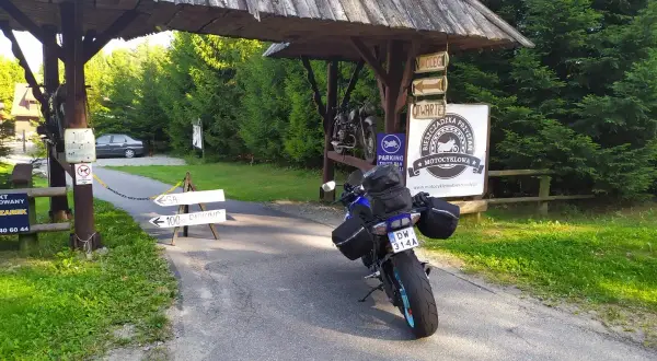 Motocykl czeka na dalszą podróż po Słowacji. Przy drogowskazie "100m parking" i znaku "Bieszczadzka Przystań Motocyklowa" zaczyna się przygoda.