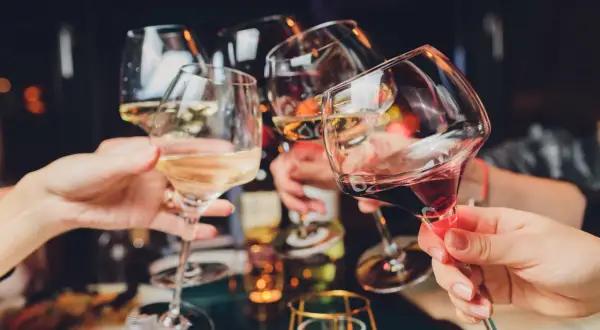 Ludzie wznoszą toasty kieliszkami z winem. Czy 5-HTP i alkohol to dobre połączenie?