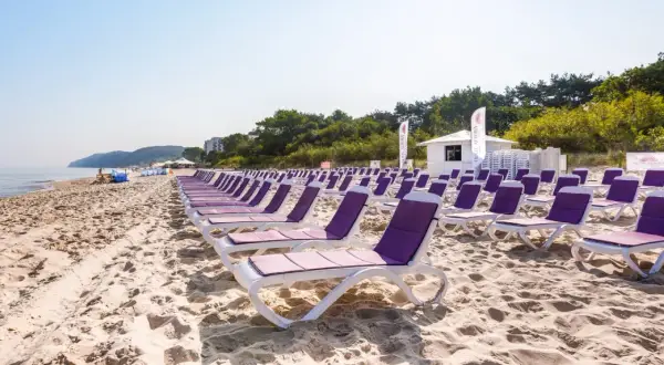 Rzędy leżaków na piaszczystej plaży, idealne na tanie wczasy nad morzem dla 2 osób z wyżywieniem.