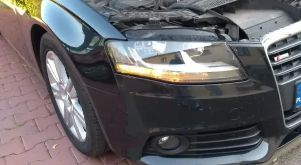 Audi A4 B8 przód: wymiana żarówki kierunkowskazu. Silnik odsłonięty, maska podniesiona.
