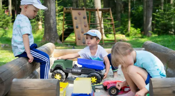 Dzieci w piaskownicy bawią się zabawkami, co wspiera ich rozwój fizyczny w wieku przedszkolnym.