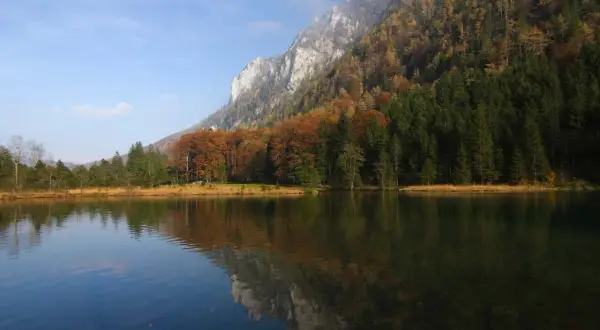 Herbstliche Farben am Falkensee Inzell, mit Bergen und Bäumen, die sich im ruhigen Wasser spiegeln.