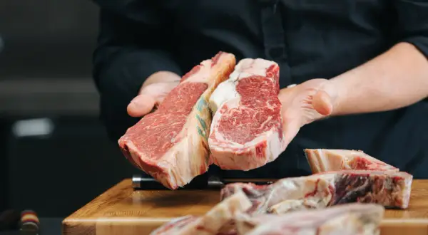 Manos sostienen dos cortes de ternera. La ternera es carne magra, ideal para una comida saludable y deliciosa.