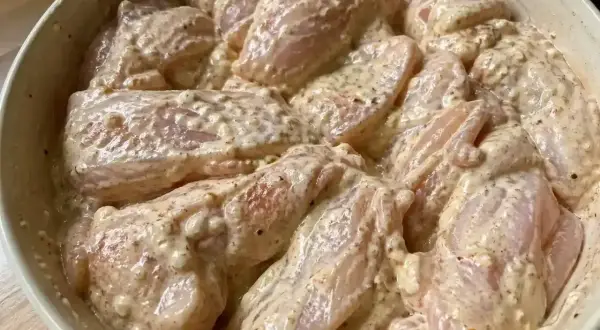 Råa kycklingbitar i en krämig marinad. Denna yoghurtmarinerade kyckling ser ut att bli otroligt saftig och smakrik.