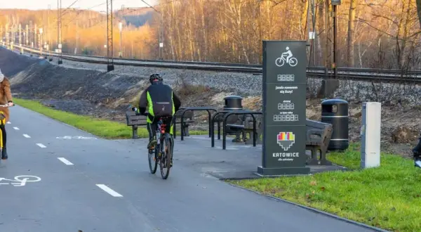 Rowerzyści na ścieżce wzdłuż torów kolejowych. Nowoczesne trasy rowerowe Śląsk zachęcają do aktywnego wypoczynku.