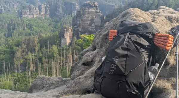 Rucksack und Wanderstöcke auf Felsen mit Bergpanorama. Alles pvc frei für umweltbewusstes Trekking.